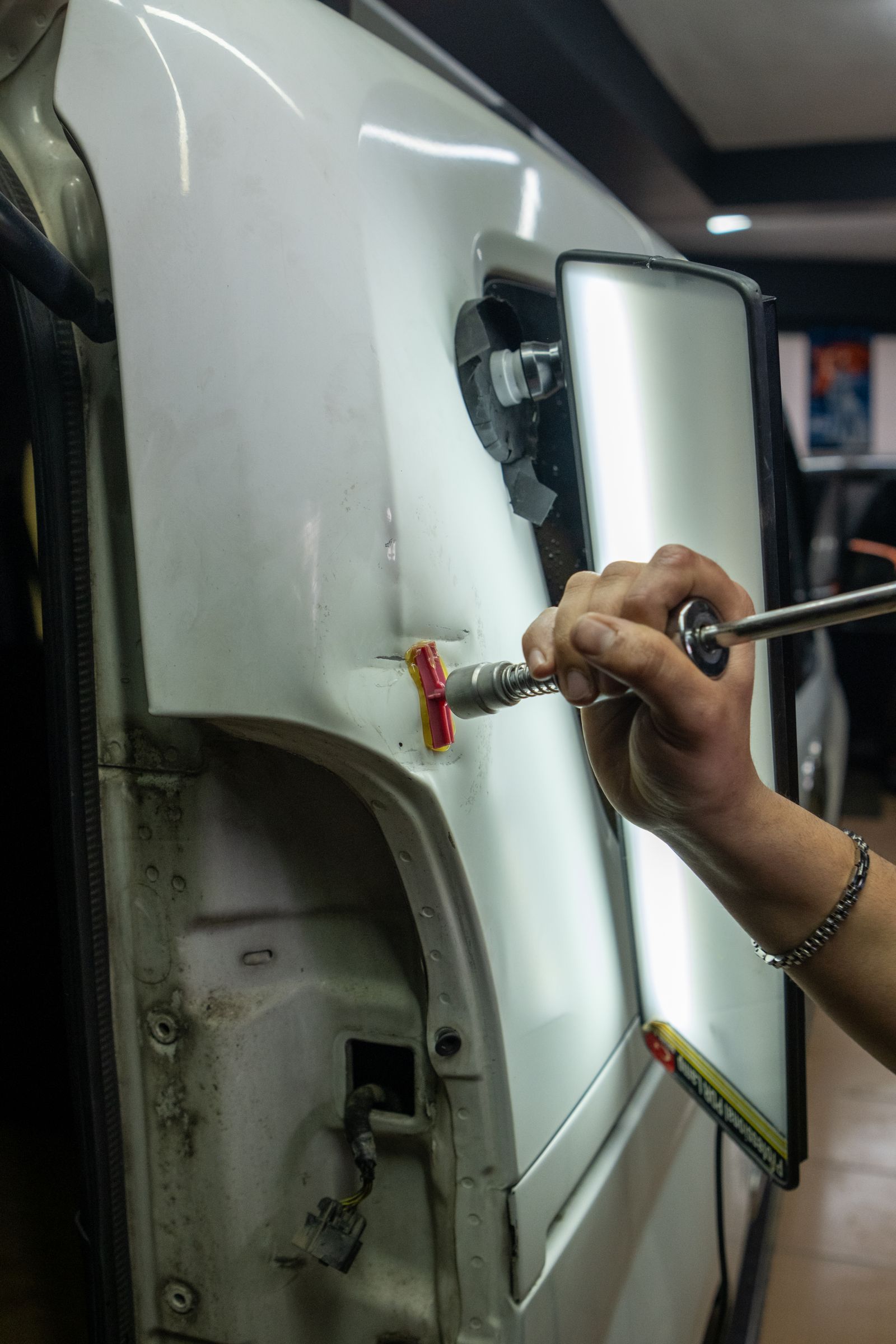 Technician working on the body of a vehicle inside the repair bay